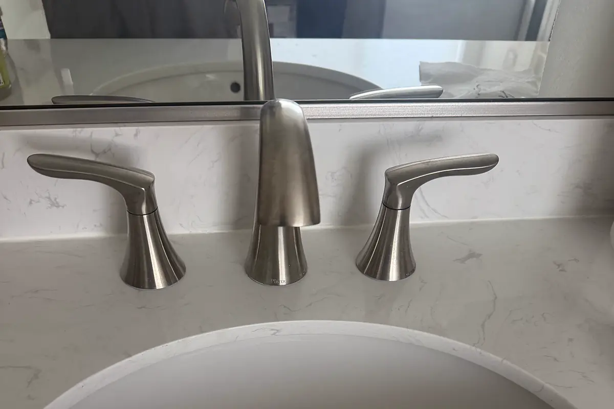 A new widespread bathroom faucet installed on a quartz vanity top.